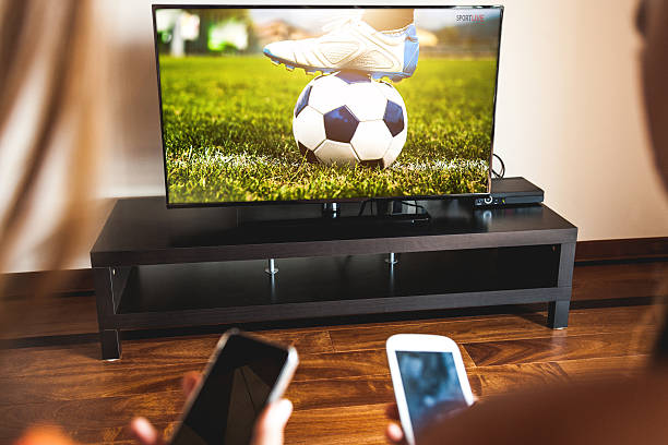 Friends using mobile phone during a soccer match on the TV.